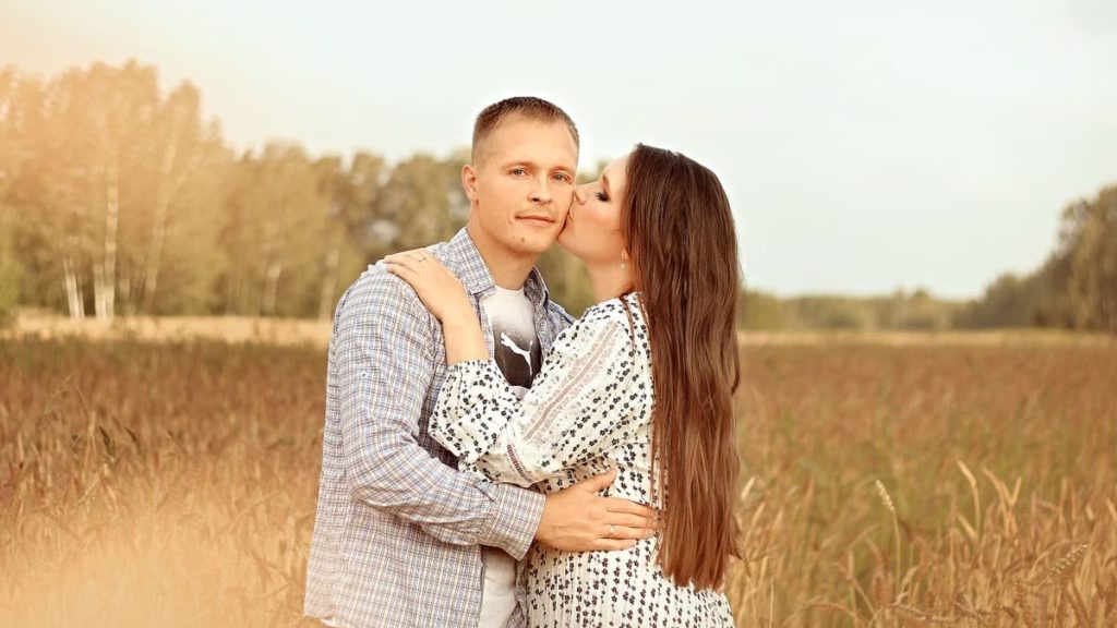 A loving couple sharing an intimate moment in a golden, sunlit field.